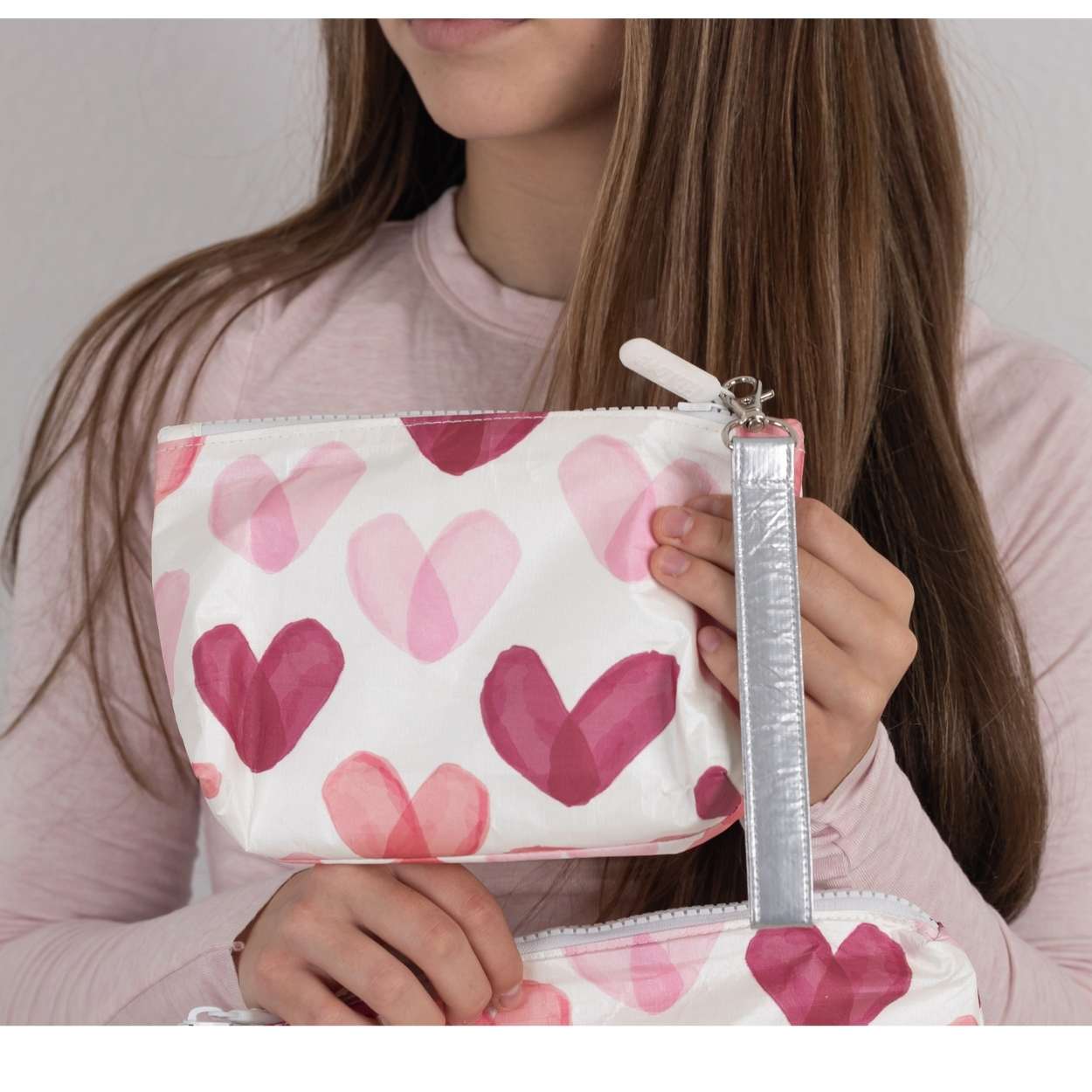 Person holding a wristlet pouch with pink heart pattern
