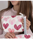 Person holding a wristlet pouch with pink heart pattern