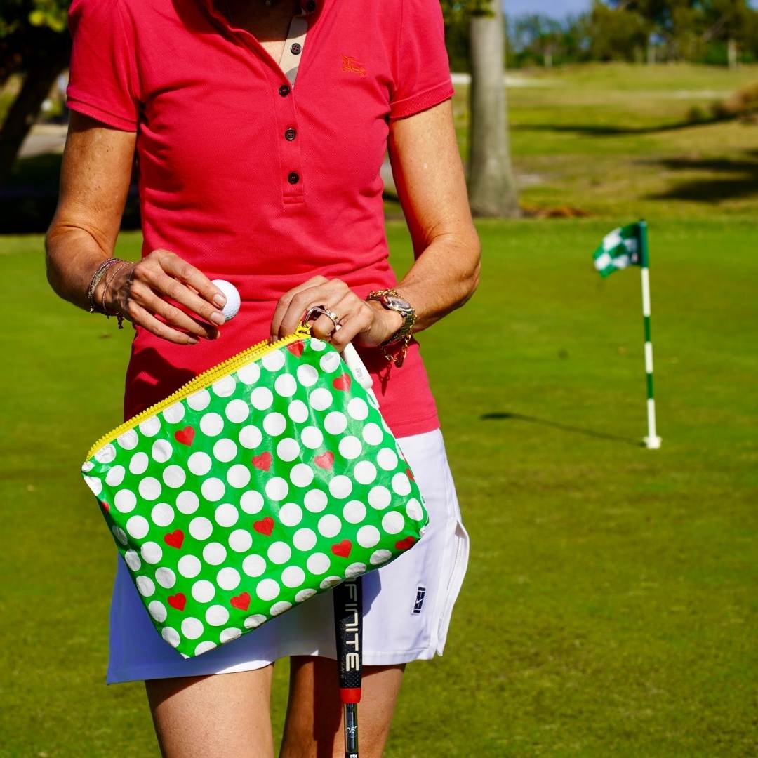 A person on a golf course holding a green  golf print bag with a golf club