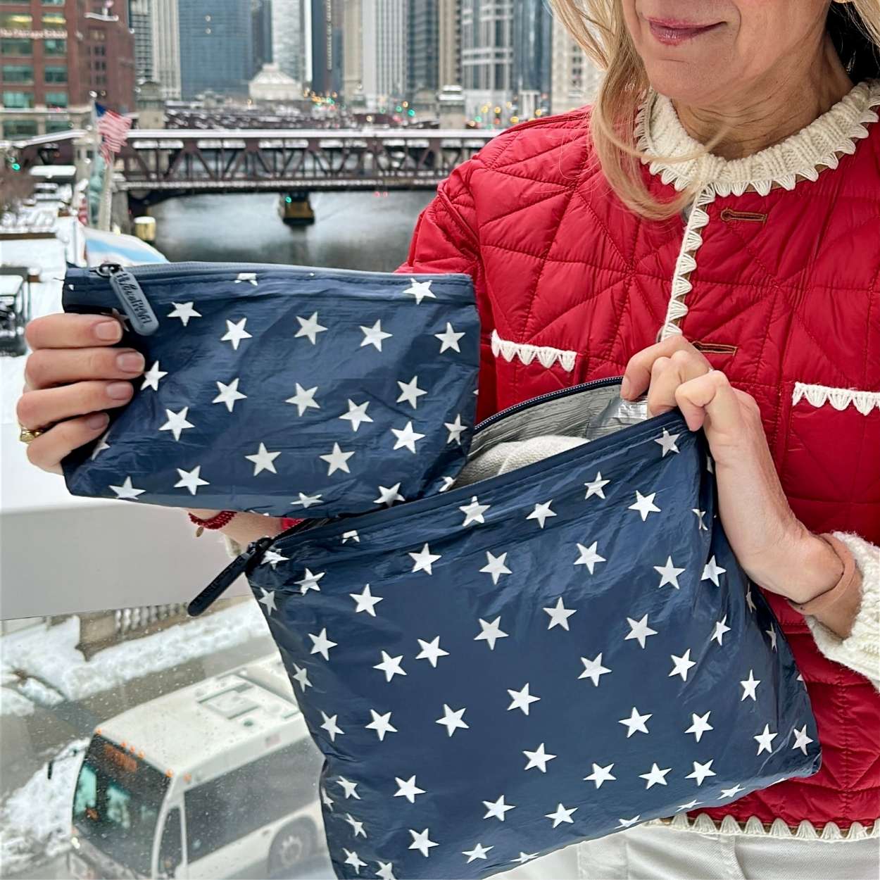 Woman in Red Jacket in city with zipper pouch in navy with Silver Stars