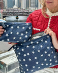 Woman in Red Jacket in city with zipper pouch in navy with Silver Stars
