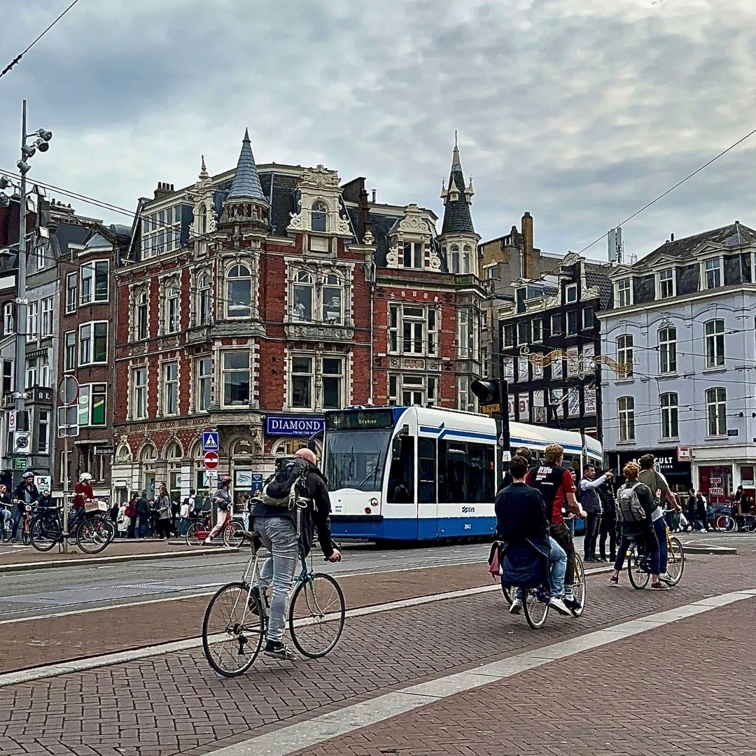 City street scene with people on bicycles and a tram in the background in Amsterdamn
