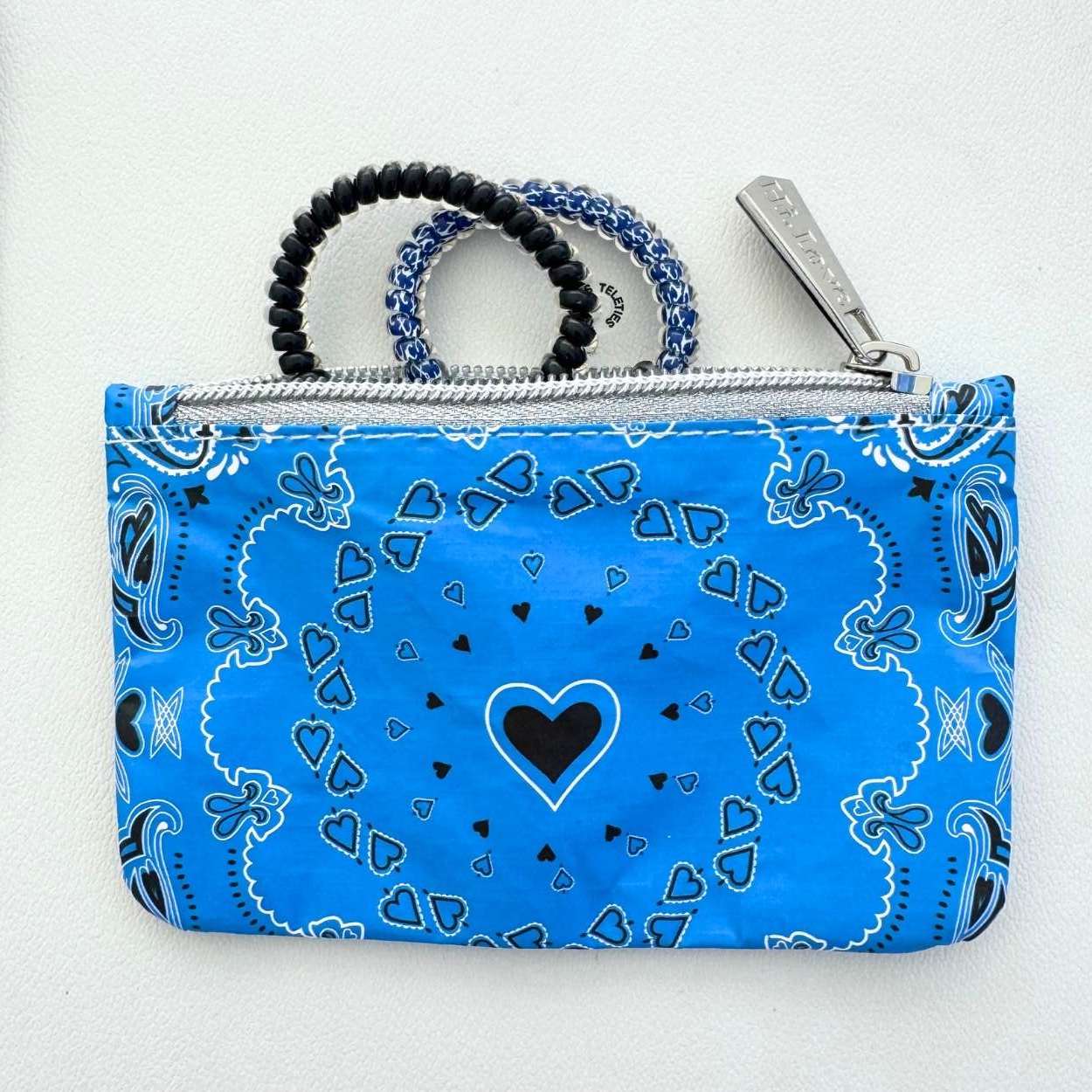 Blue bandana-patterned pouch with a black heart design on a white background