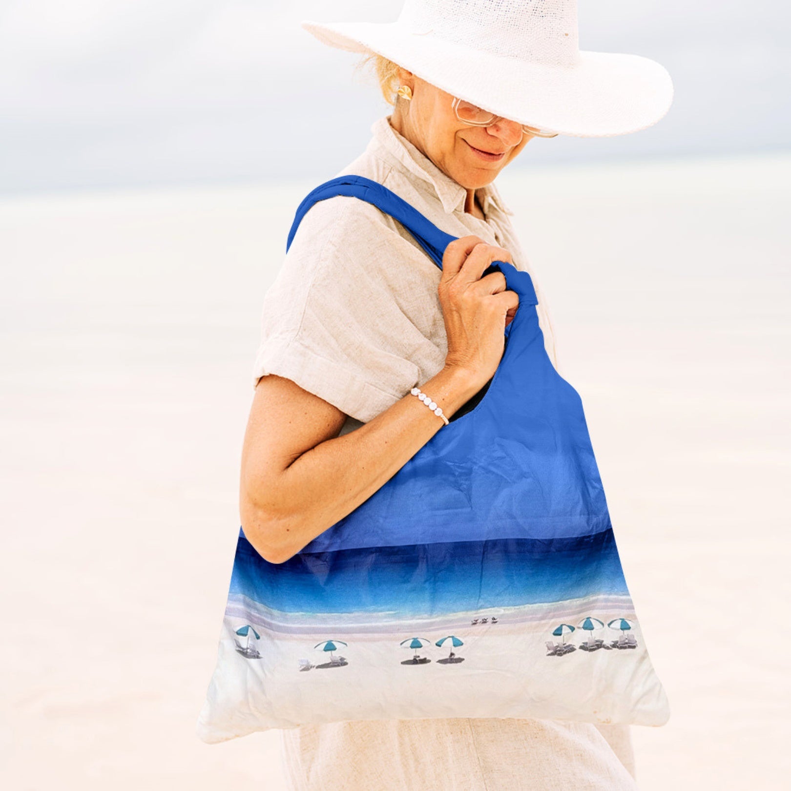Woman on the beach with a beach scene printed tote bag on her shoulder
