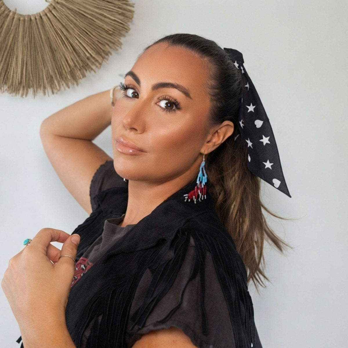Model wearing the black Signature scarfette with white hearts, moons and stars tied around her ponytail.