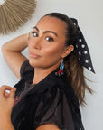 Model wearing the black Signature scarfette with white hearts, moons and stars tied around her ponytail.