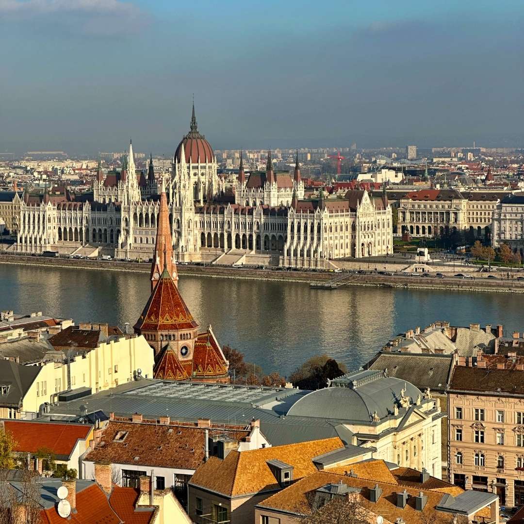 Cityscape with a large building by a river, likely a parliament, with a clear sky in Budapest Hungary