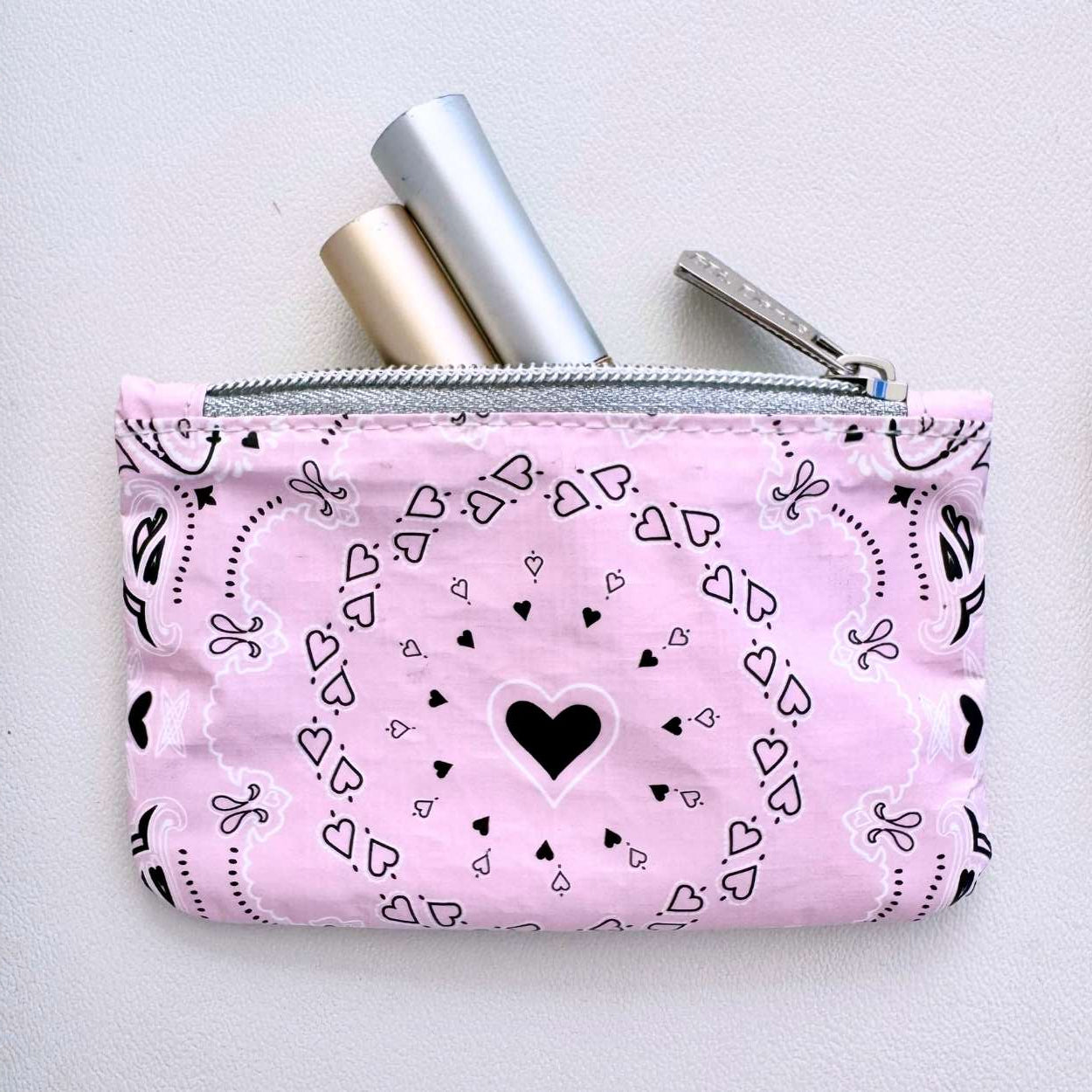Pink pouch with black heart bandana pattern on a light gray background