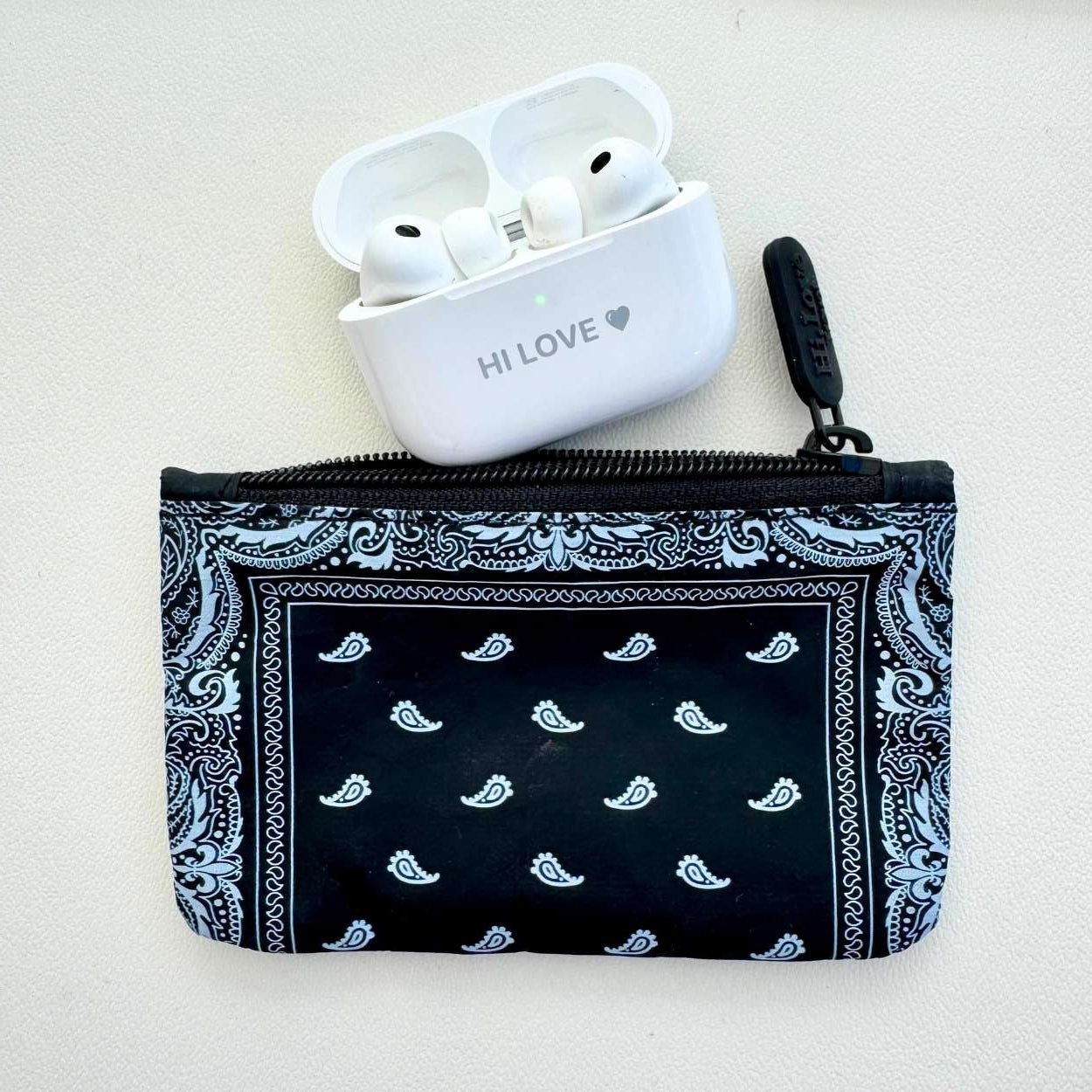 Black bandana-patterned pouch with white earbuds on a light gray background