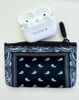 Black bandana-patterned pouch with white earbuds on a light gray background