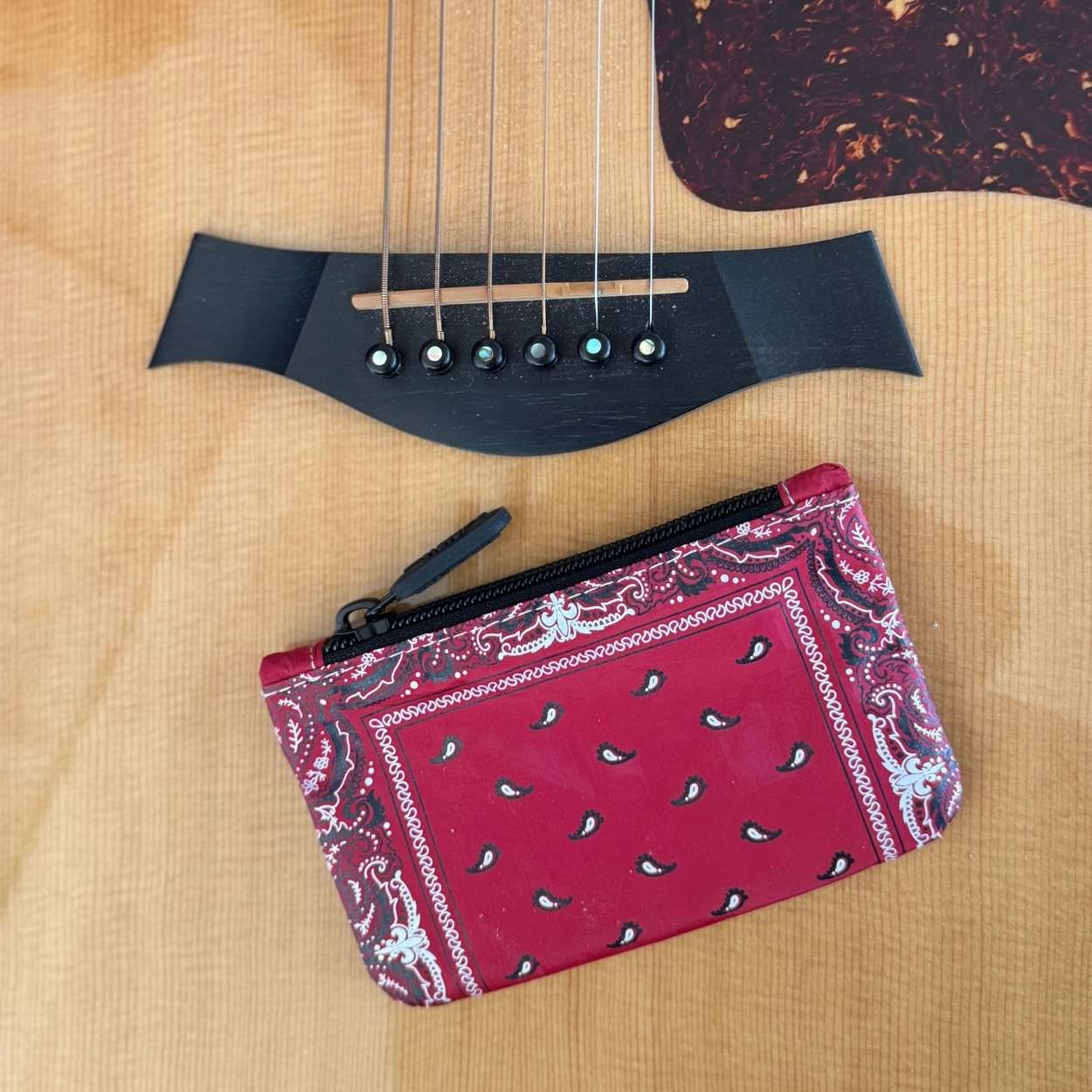Red bandana-patterned pouch on an acoustic guitar