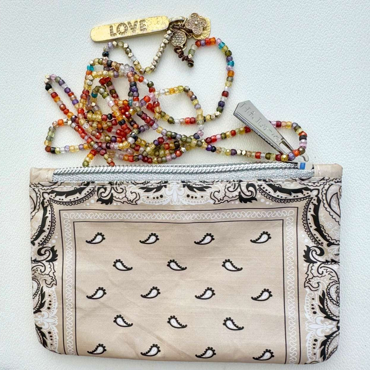 Colorful beaded necklace with charms and a patterned bandana pouch on a light background
