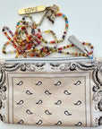 Colorful beaded necklace with charms and a patterned bandana pouch on a light background