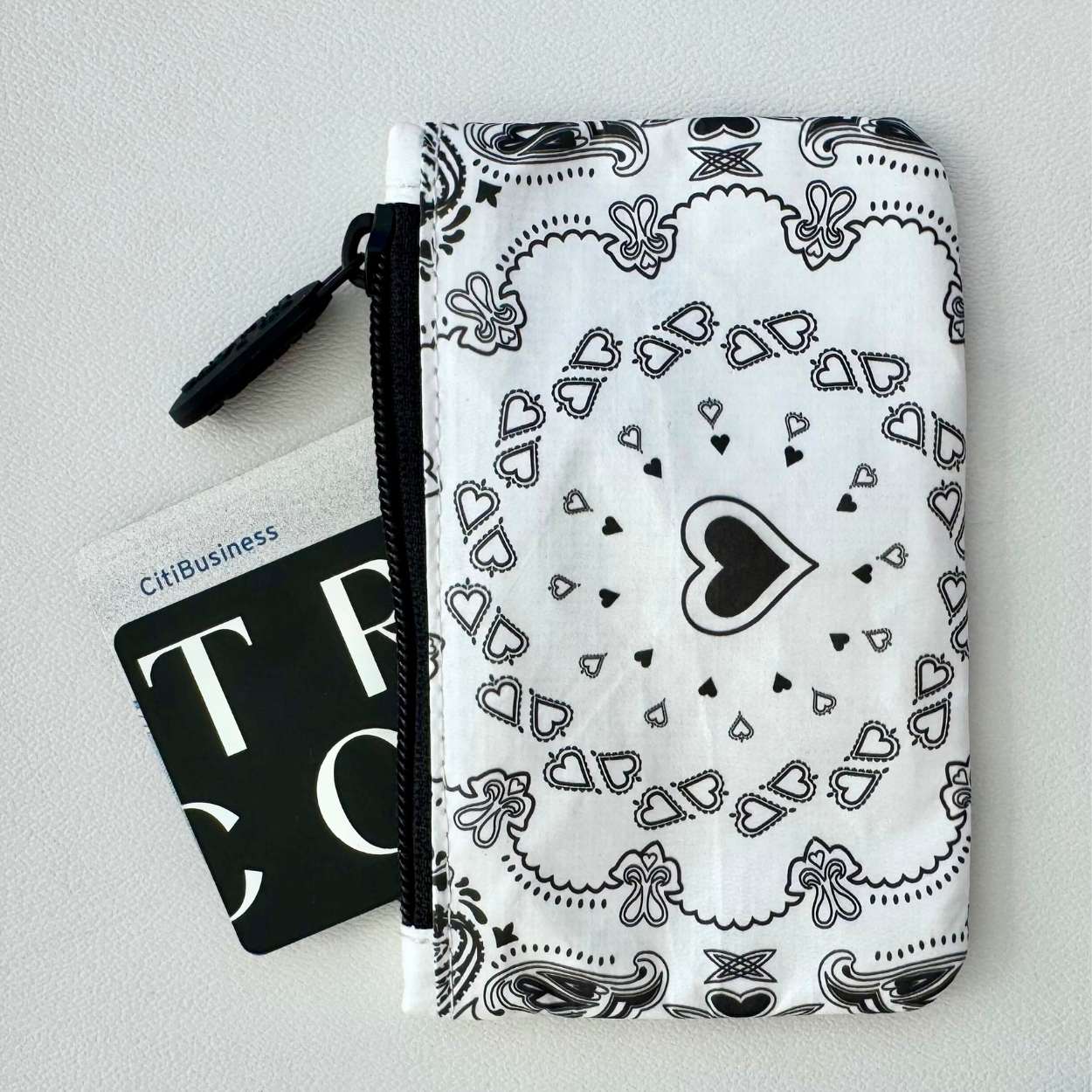 Black and white bandana patterned pouch with a card on a light gray background