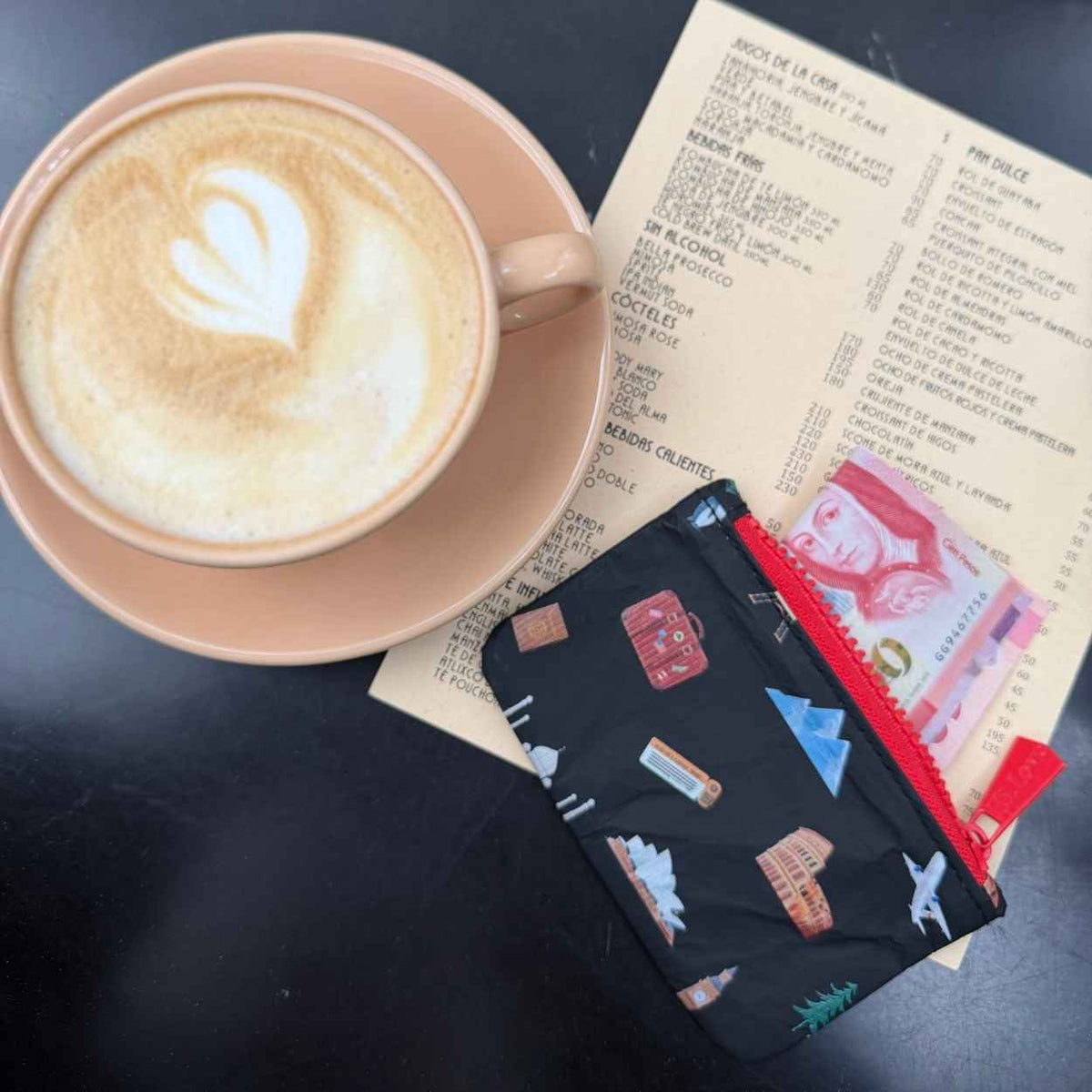 Coffee, menu, and card pouch in black with world landmark print on black backgrouns. 