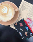 Coffee, menu, and card pouch in black with world landmark print on black backgrouns. 