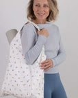 Woman holding a yoga patterned bag against a plain background