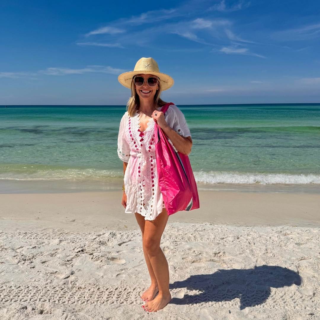 women standing on the beach holding a bright pink beach tote