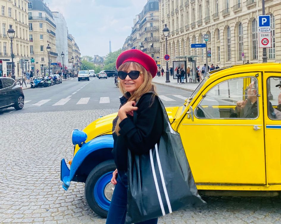 Woman in streets of Paris, France wearing red beret, black top, jeans, and holding the carryall tote bag in black with white stripes