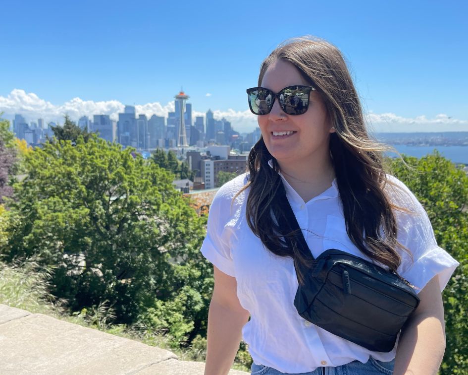 Girl wearing a black crossbody fanny pack with the view of Seattle skyline in the background.