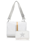 White shimmer crossbody purse with adjustable strap and matching mini zip pouch with silver star, shown together against white background.