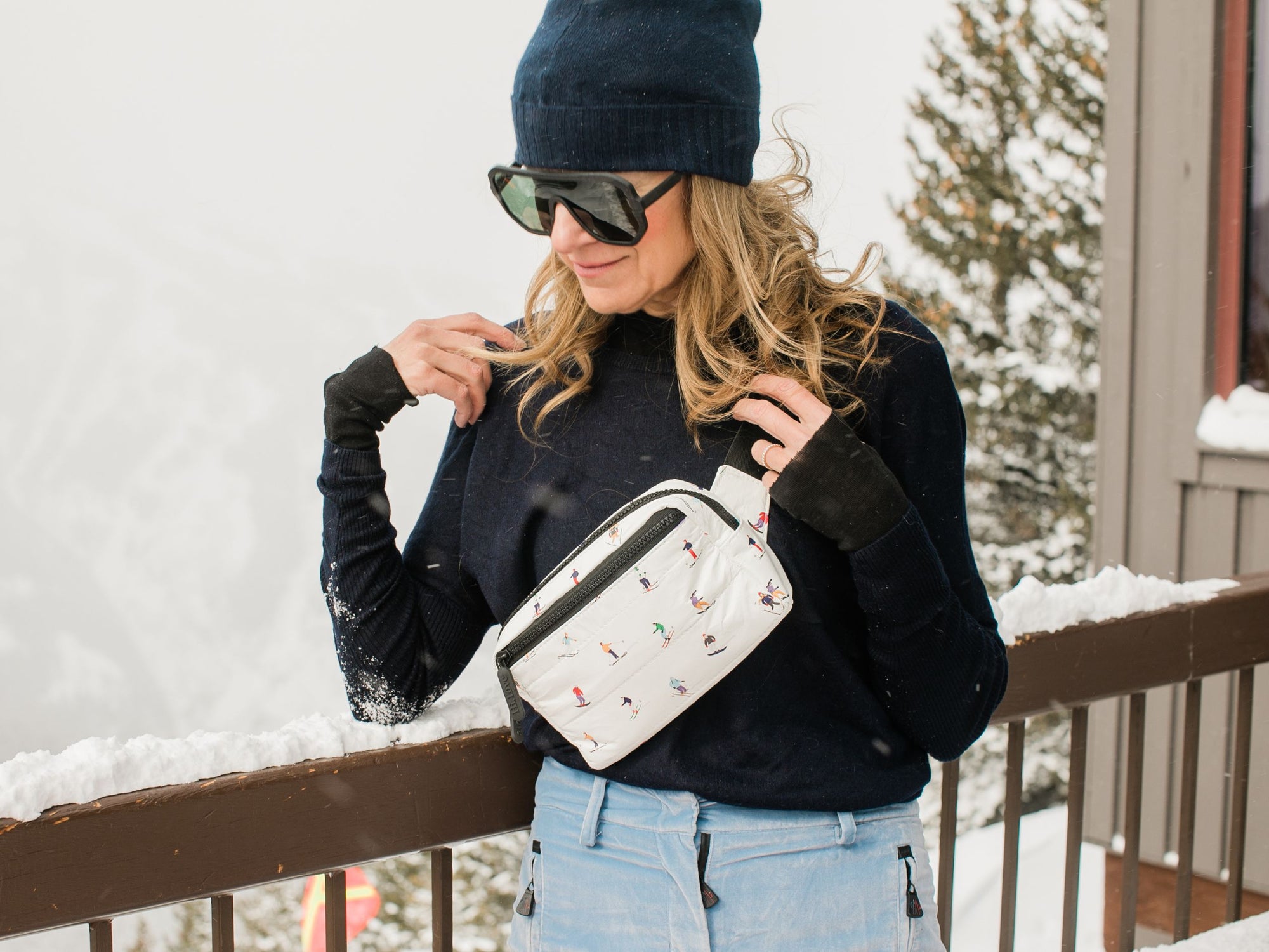woman on balcony in snow wearing Dancing skiers puffer crossbody fanny pack belt bag