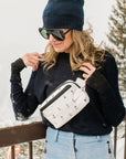 woman on balcony in snow wearing Dancing skiers puffer crossbody fanny pack belt bag