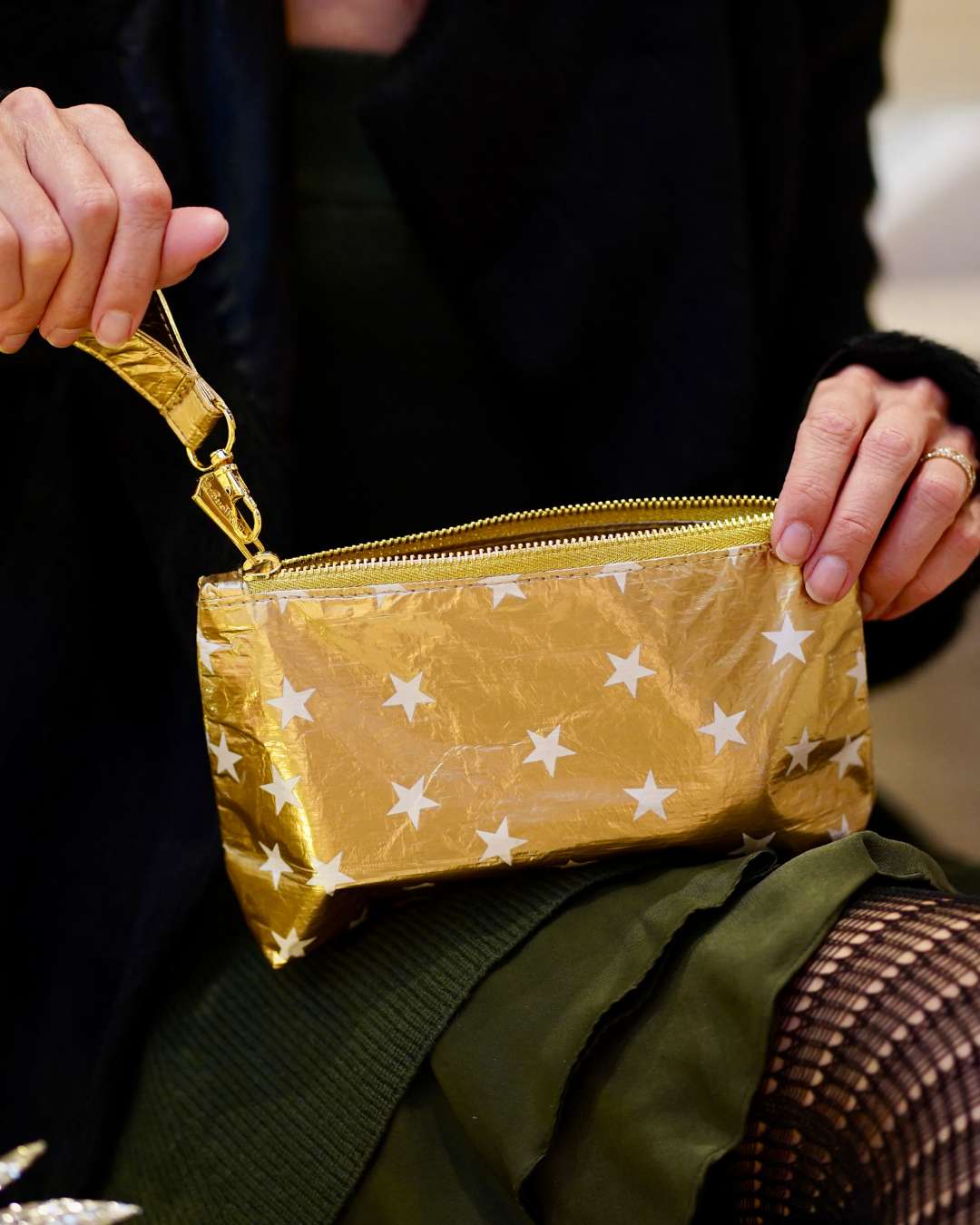 Gold pouch with star pattern held by a person