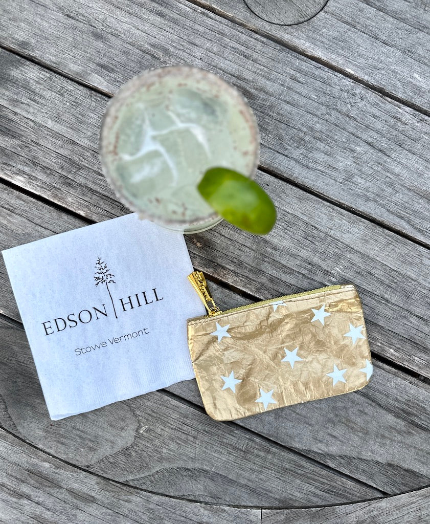 Zipper Pouch in Gold with stars on wood table at resort