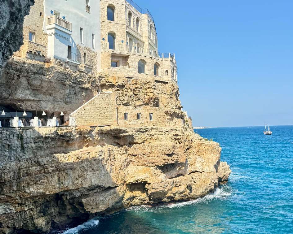 Cliffside buildings overlooking the ocean with a clear blue sky in Italy