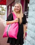 Young woman outside a shop holding a hot pink tote bag over her shoulder