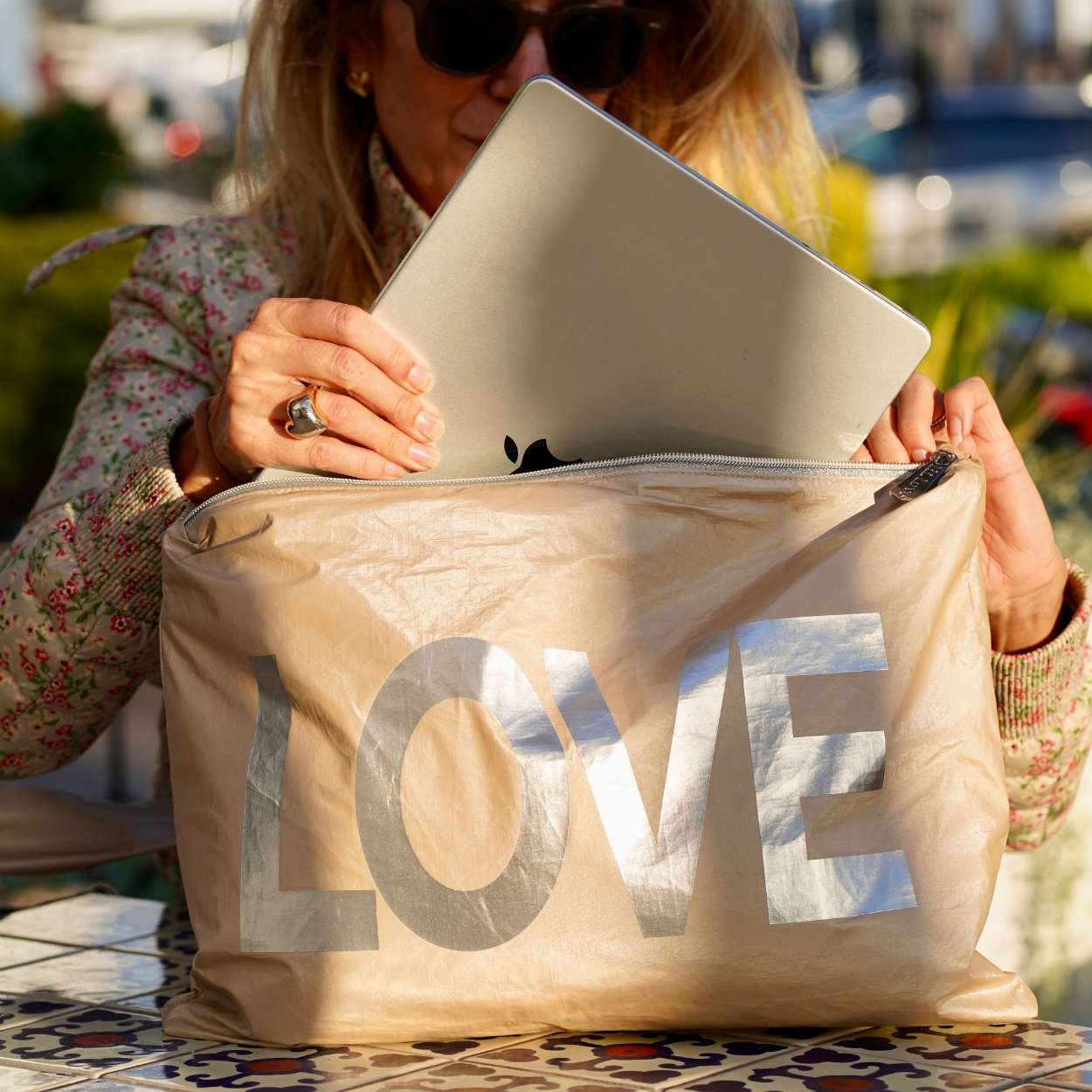 Person holding a beige bag with 'LOVE' printed on it, outdoors.