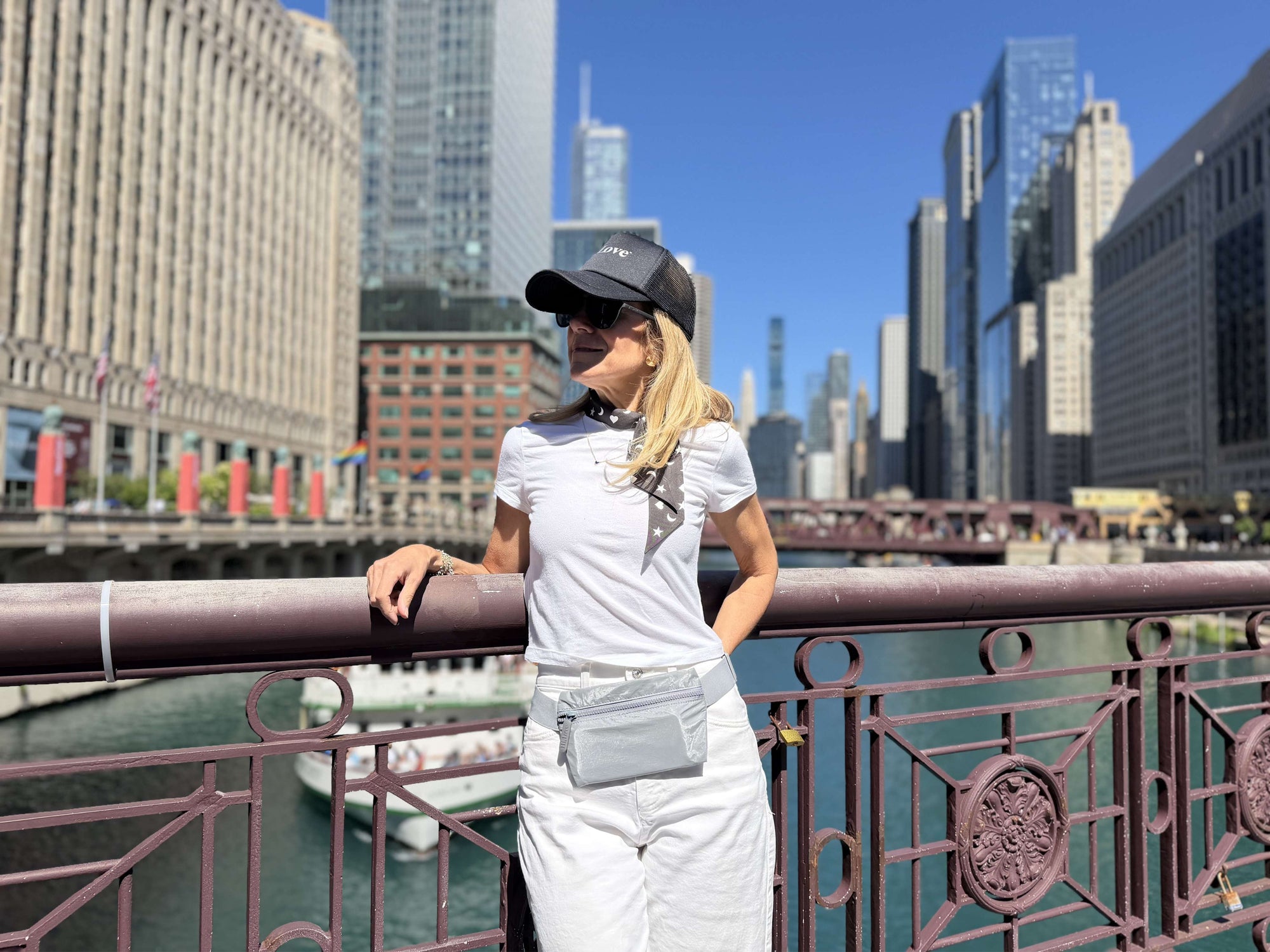 Person in white outfit and gray belt bag with city skyline and river in background