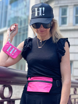 Woman wearing hot pink fanny pack and holding hot pink wristlet