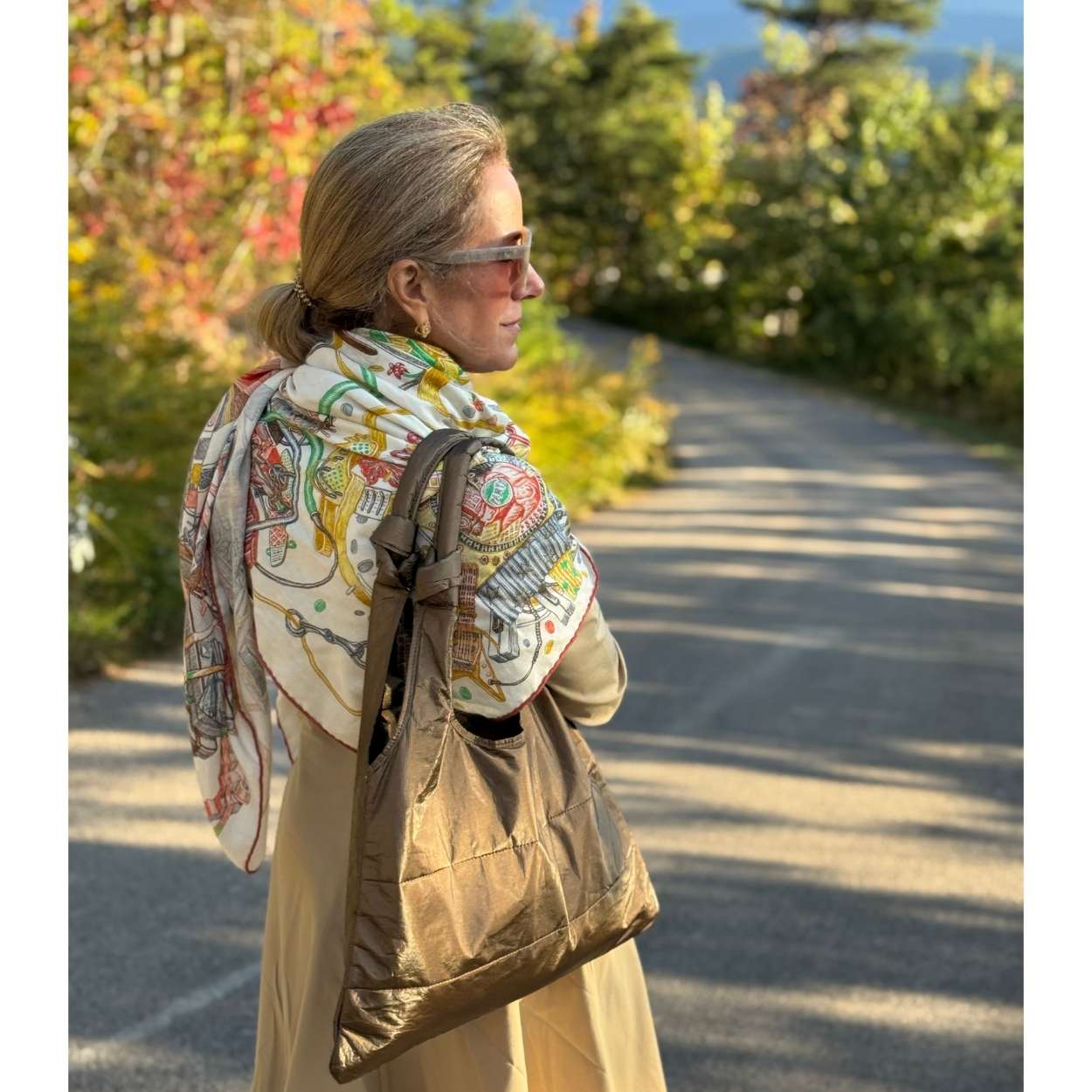 Woman on road wearing colorful scarf and tote bag in shimmer bronze