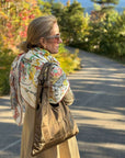 Woman on road wearing colorful scarf and tote bag in shimmer bronze