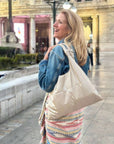 Woman with a beige tote bag walking outdoors in an urban setting
