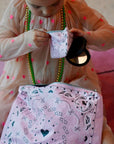 Child holding a pink bandana patterned pouch with a mirror inside