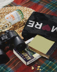 Plaid picnic blanket with black with "AMORE" medium zipper pouch, bottled water, book, and binoculars on top
