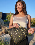 Women with tan silk top and black skirt using a black zipper pouch with gold stars 