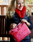 Woman wearing red scarf holding a red bandana patterned zipper clutch bag