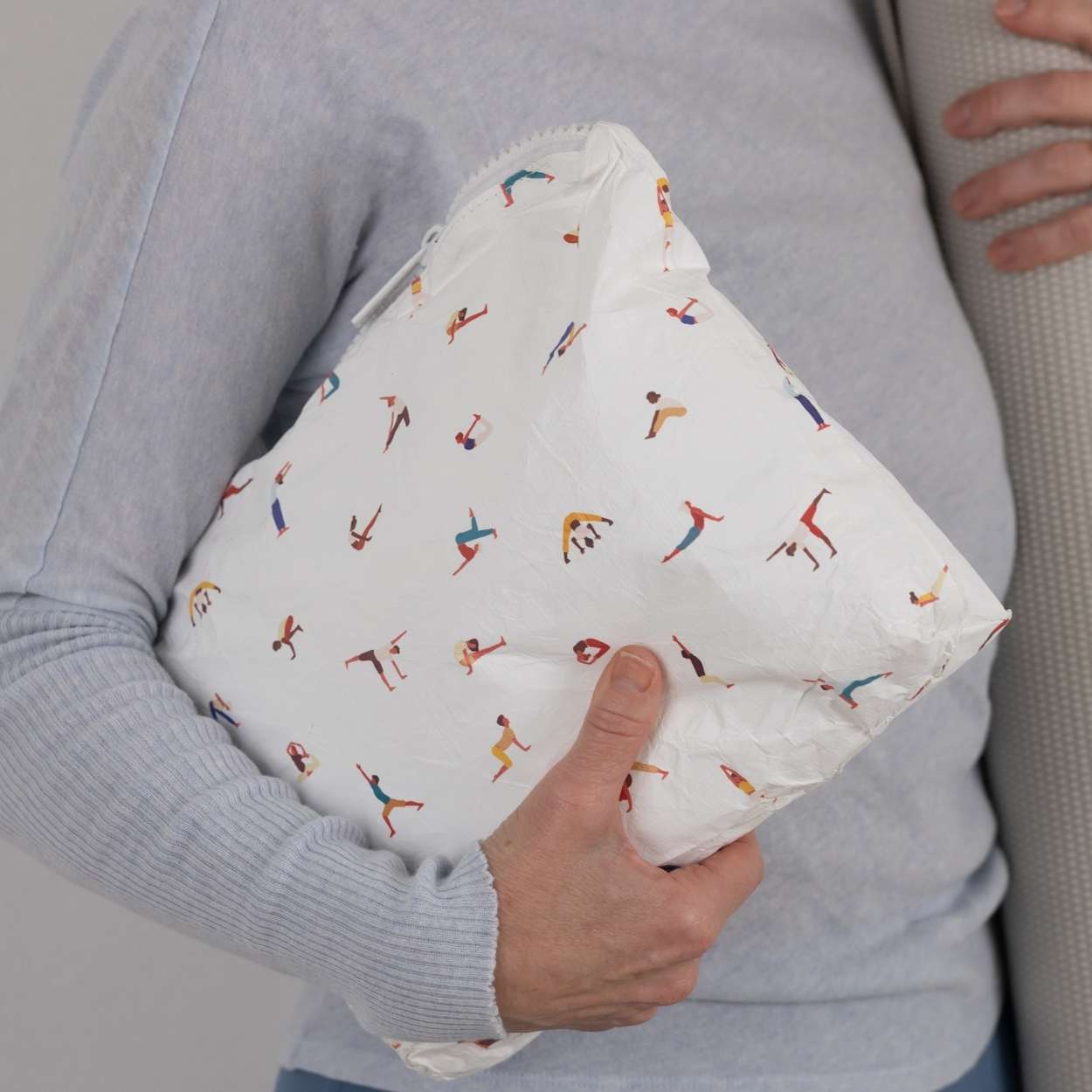 Person holding a white pouch with yoga pattern on it.