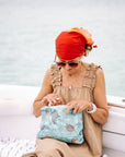 Woman in a boat looking inside sea green turtle patterned zipper pouch