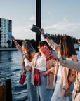 Group of women holding bandana pouches on a boat by the water with buildings in the background