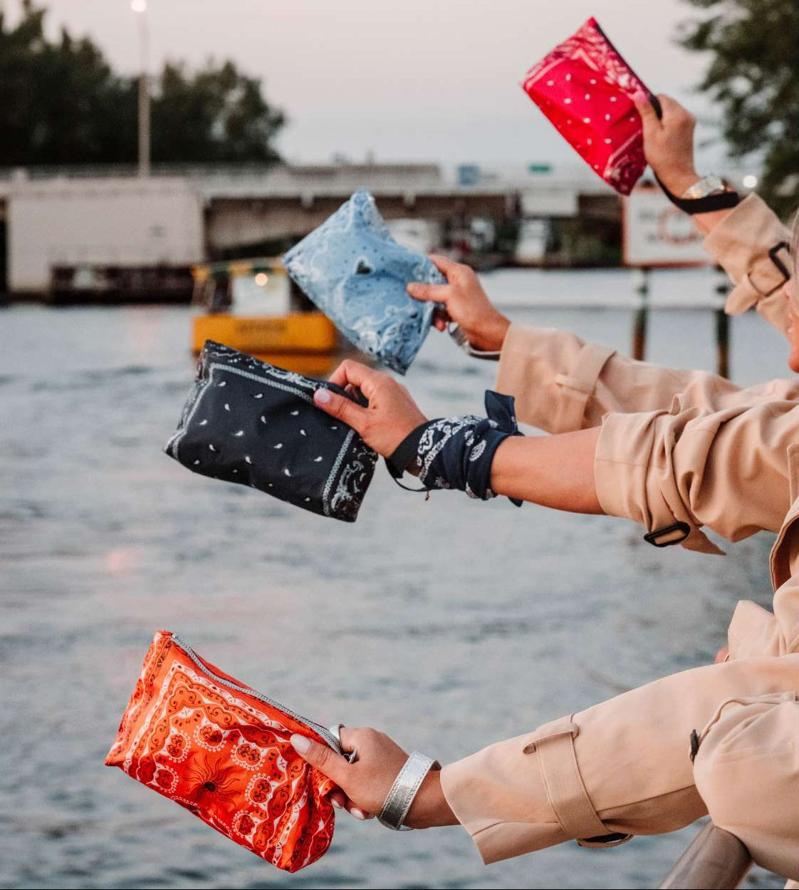 People holding reusable bandana pouches by a waterfront
