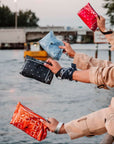People holding reusable bandana pouches by a waterfront