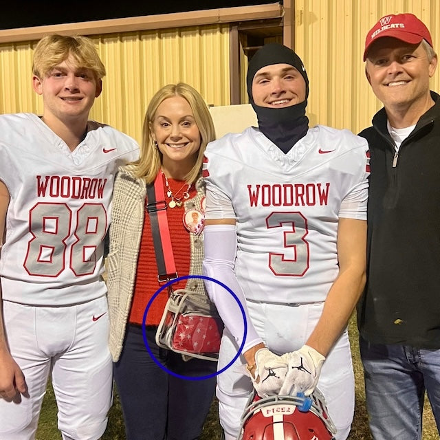 family together at a football game with a red zipper pouch in her clear bag.