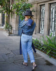 Woman in denim outfit with hat carrying navy bandana pouch walking on a city street