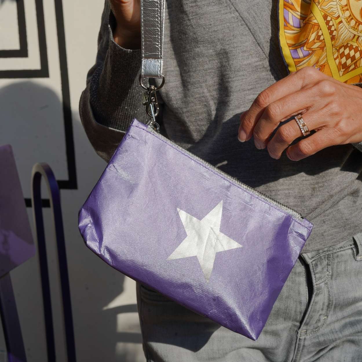 Person holding a purple pouch with a white star design.