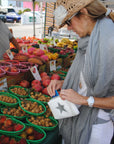 Woman at farmers market carrying white pouch with silver star